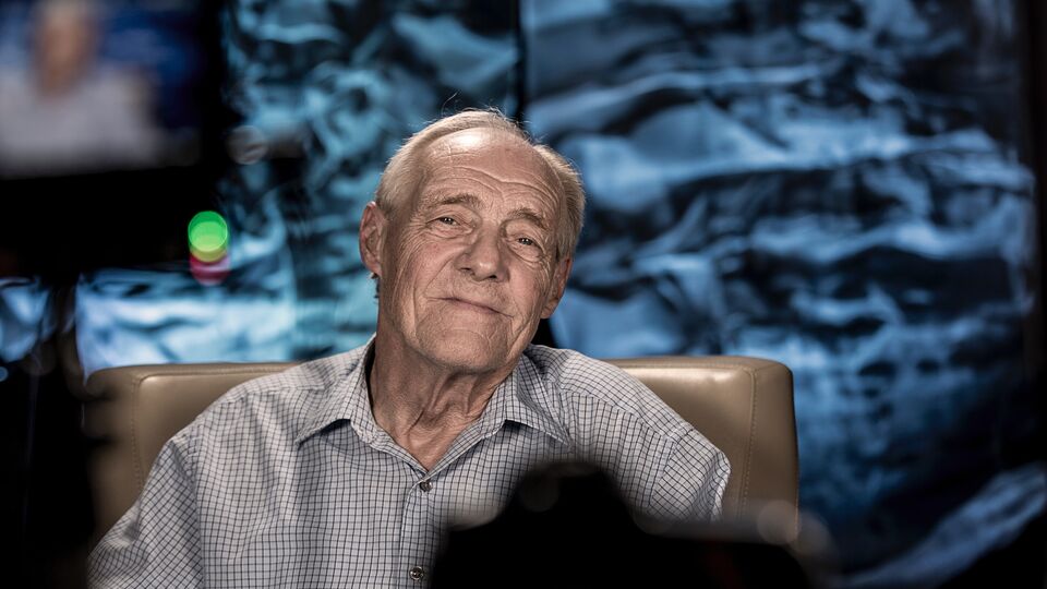 Man, sitting in a chair, faces a camera