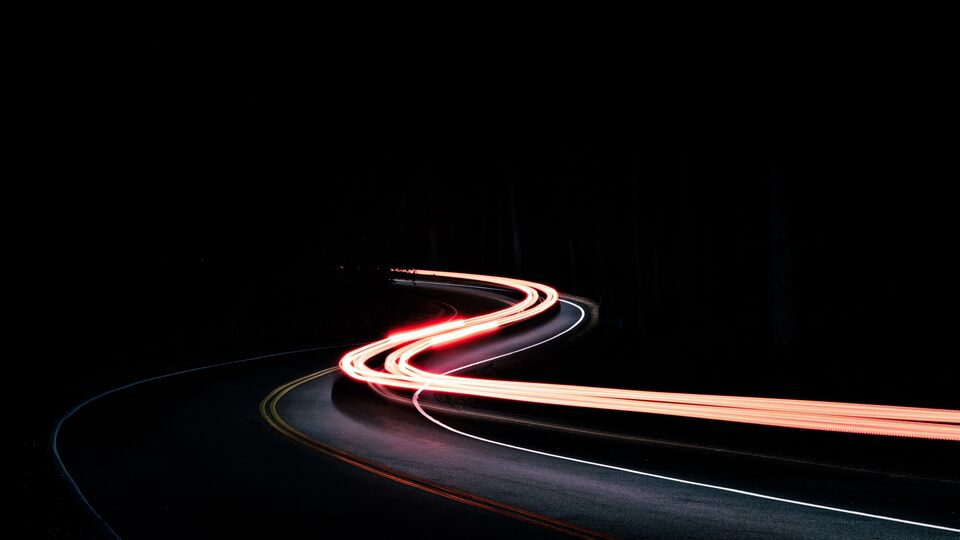Streaks of car lights bending around a road at night