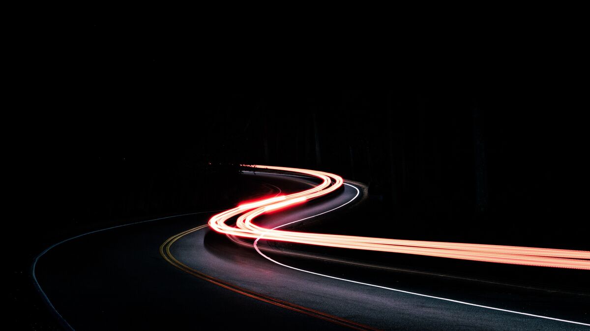 Streaks of car lights bending around a road at night