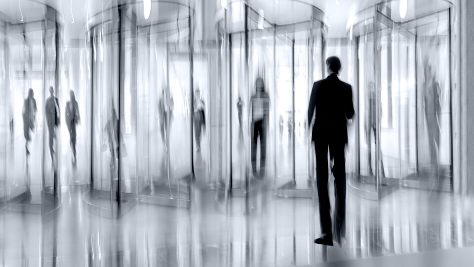 Blurry people using blurry revolving doors