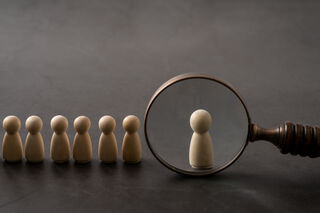 Magnifying glass held against one of several small wooden figures
